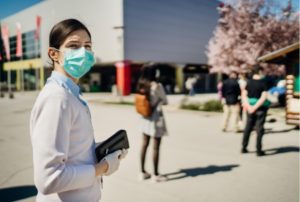 A woman standing in line wearing a medical mask