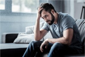 A man sitting leaning his head on his hand