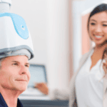 Clinician monitoring a patient who is wearing a TMS helmet and getting TMS therapy.
