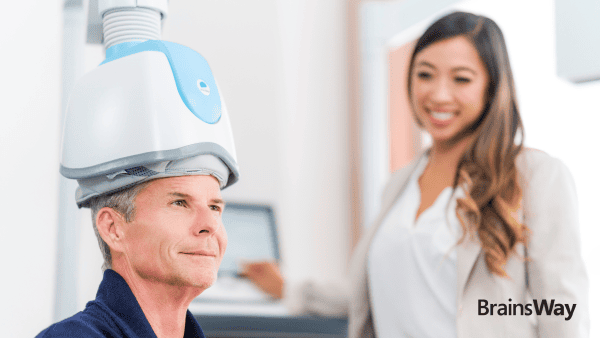 Clinician monitoring a patient who is wearing a TMS helmet and getting TMS therapy.